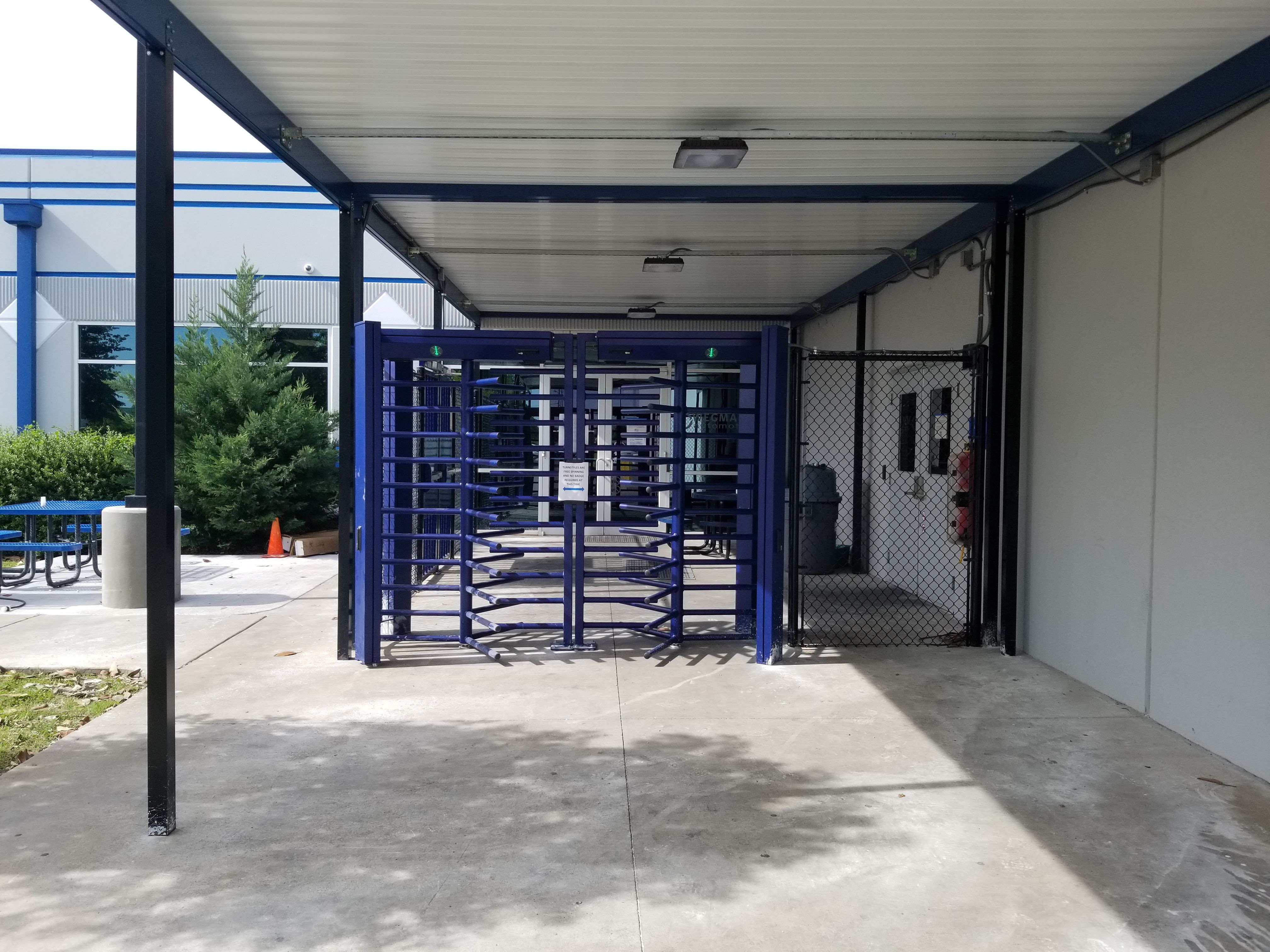 Photo of DormaKaba FTS-E02 full-height turnstiles with black, vinyl chain link fencing.