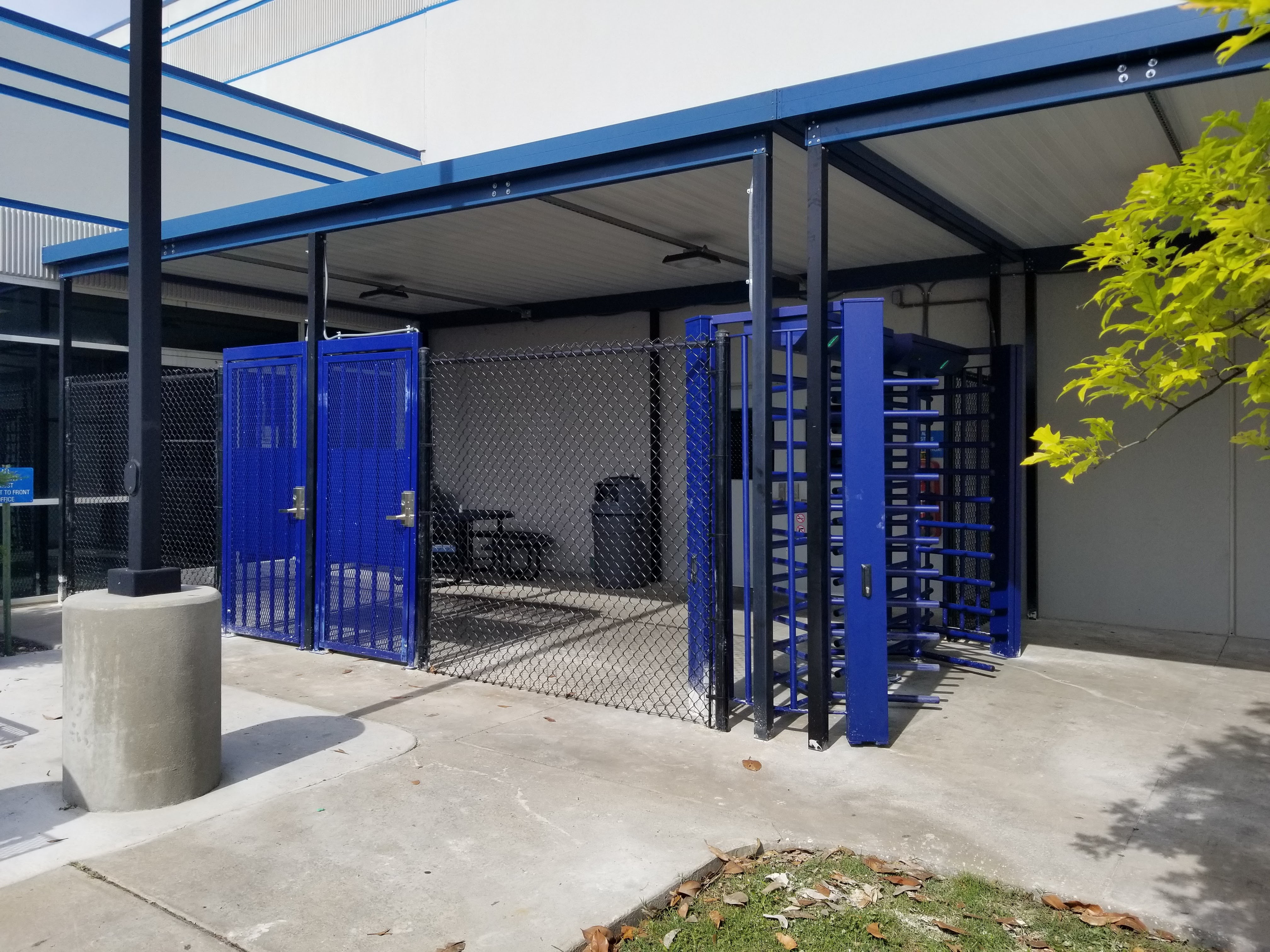 Photo of DormaKaba FTS-E02 full-height turnstiles with black, vinyl chain link fencing.