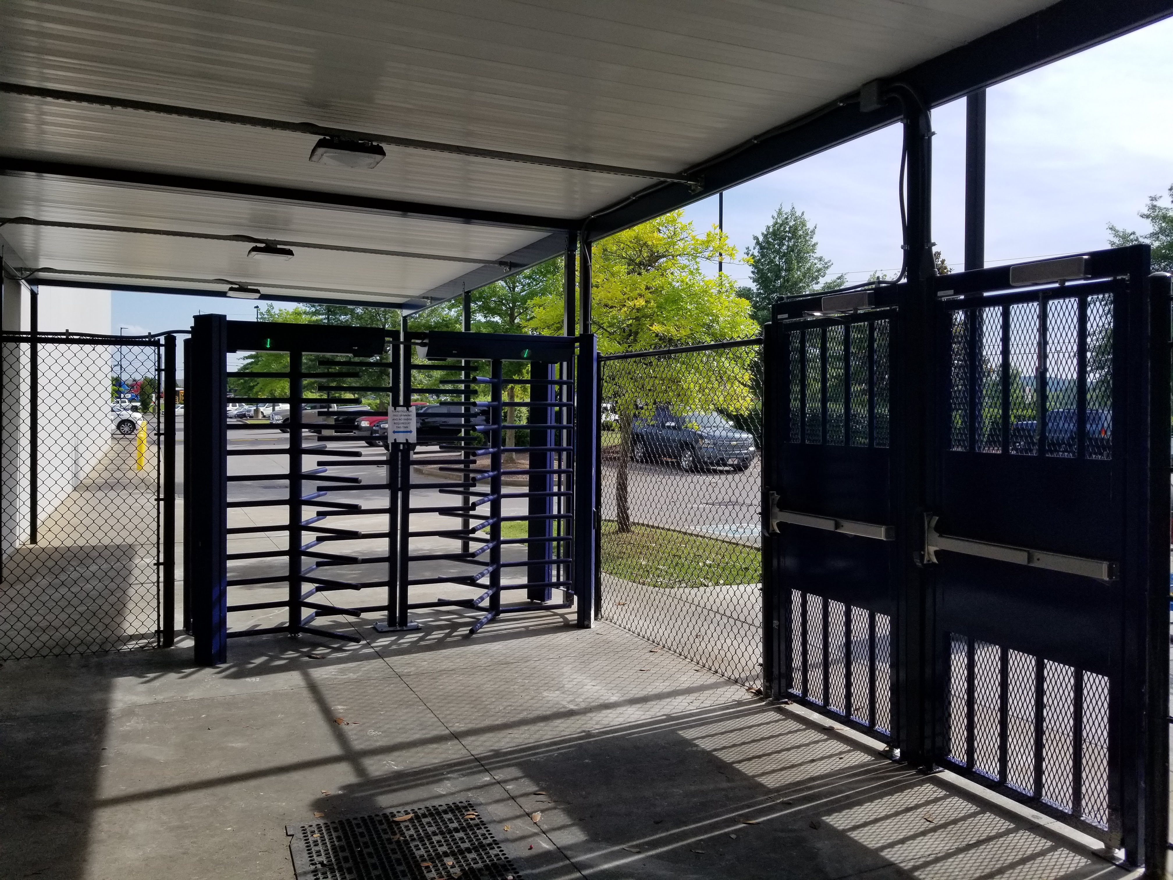 Photo of DormaKaba FTS-E02 full-height turnstiles with black, vinyl chain link fencing.