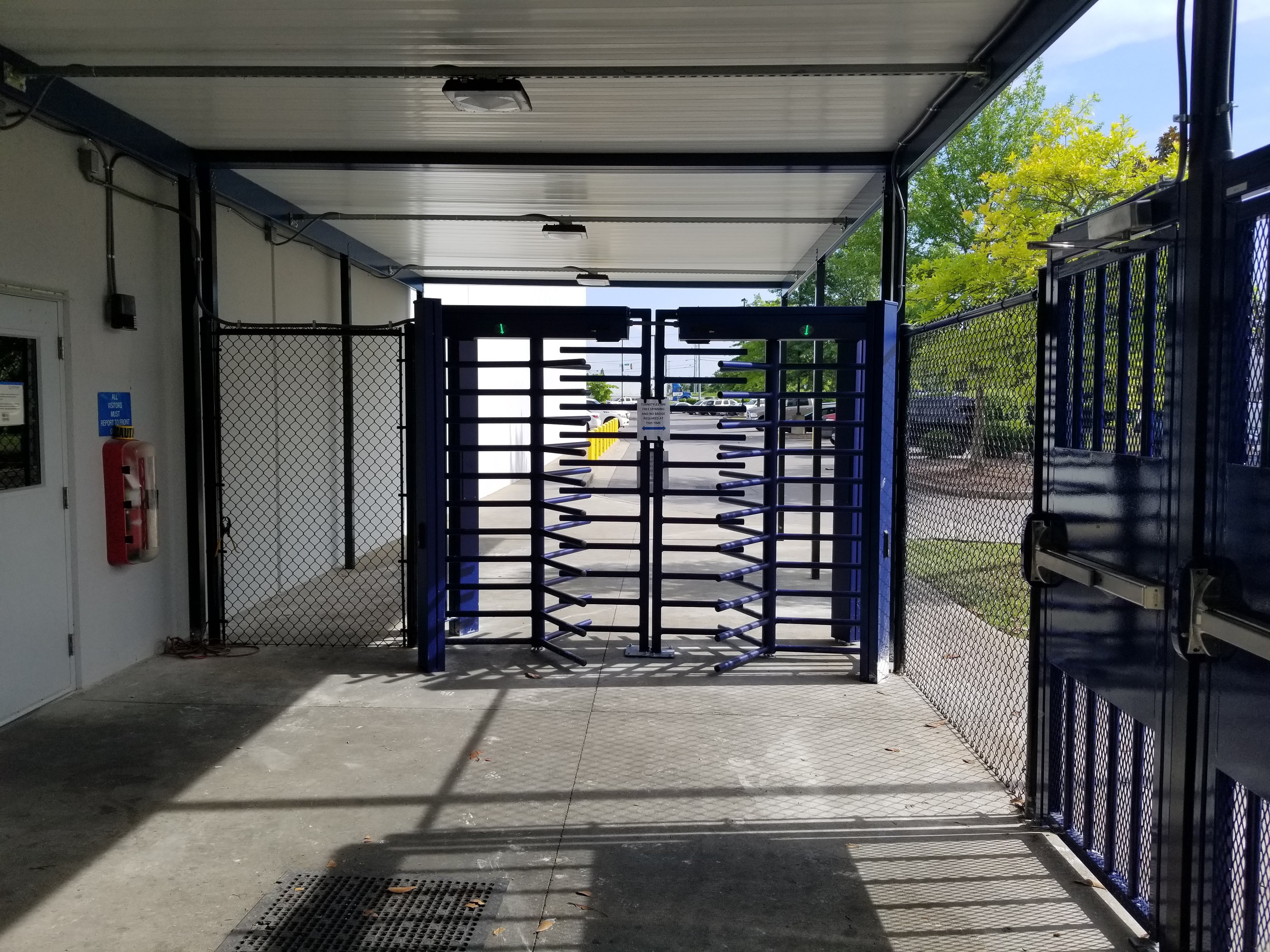 Photo of DormaKaba FTS-E02 full-height turnstiles with black, vinyl chain link fencing.